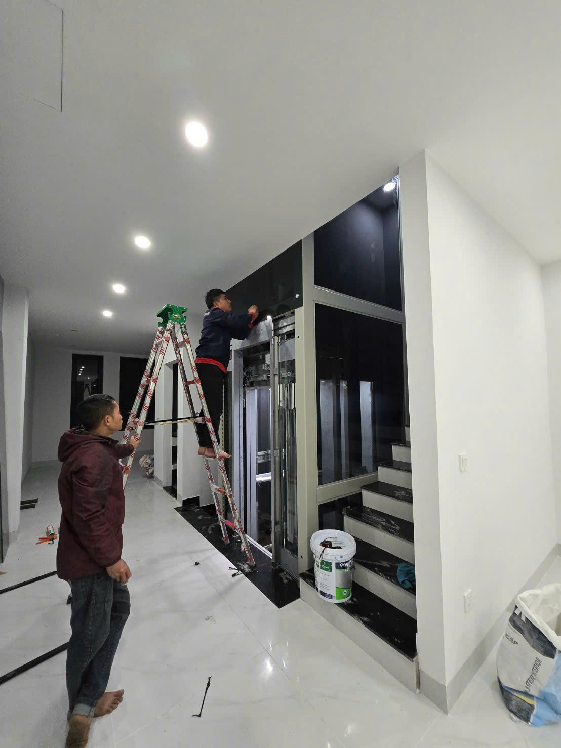 Thi công lắp đặt thang máy gia đình cạnh cầu thang trong nhà hiện đại